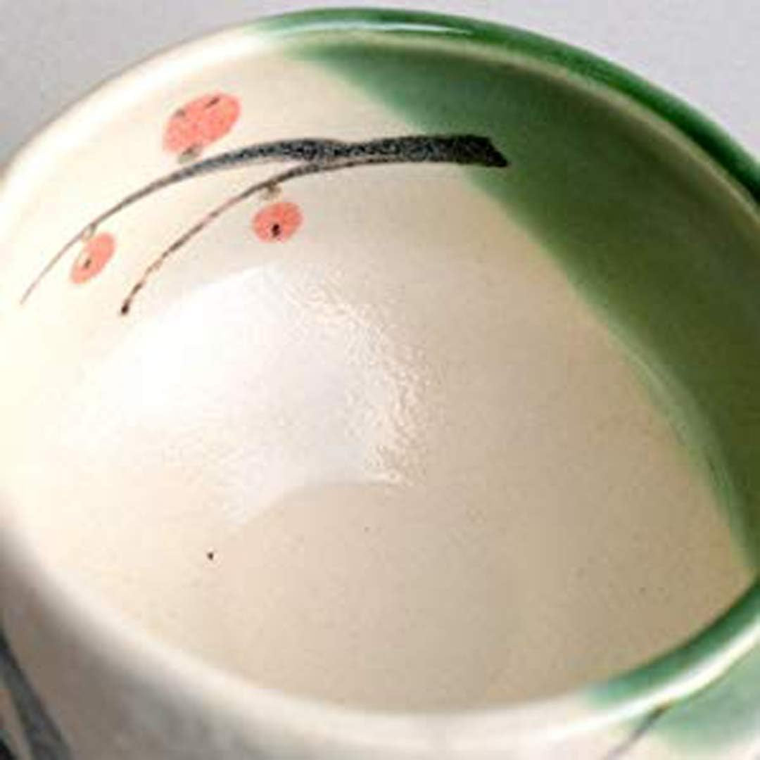 Close on the inside of the bowl, a plum branch painted in black with red blossoms