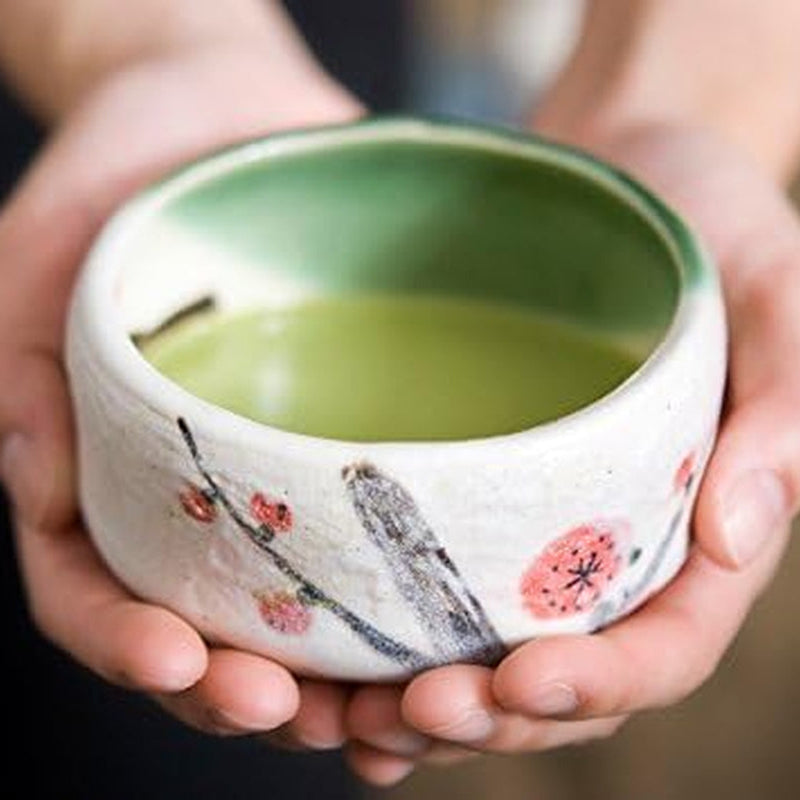 The bowl held in two hands, filled with whisked matcha