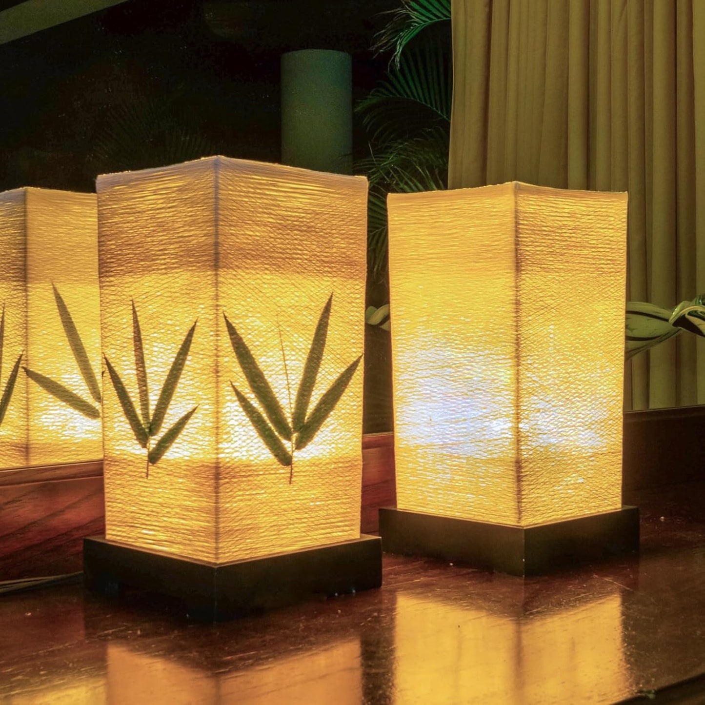 Two of the lanterns lit side by side on a dark wooden surface