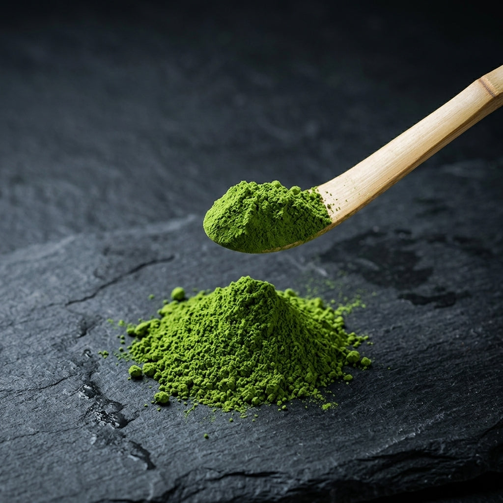 Bright green matcha powder on a bamboo scoop, above a mound of sifted powder