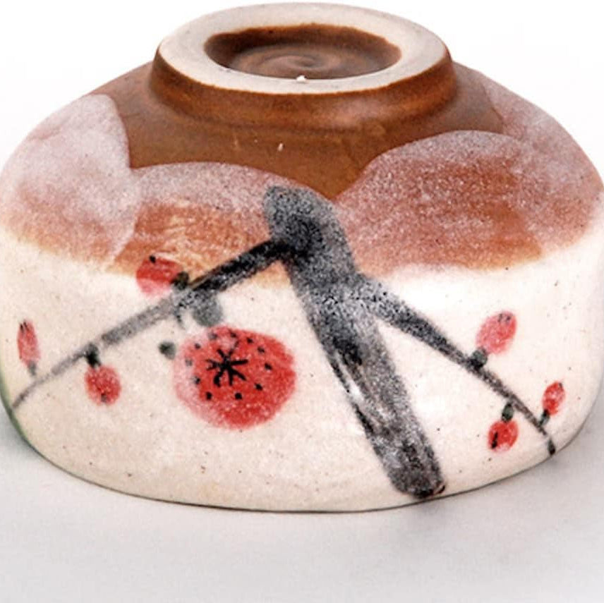 The bowl upturned to show its foot, bare brown clay above the painted plum branch