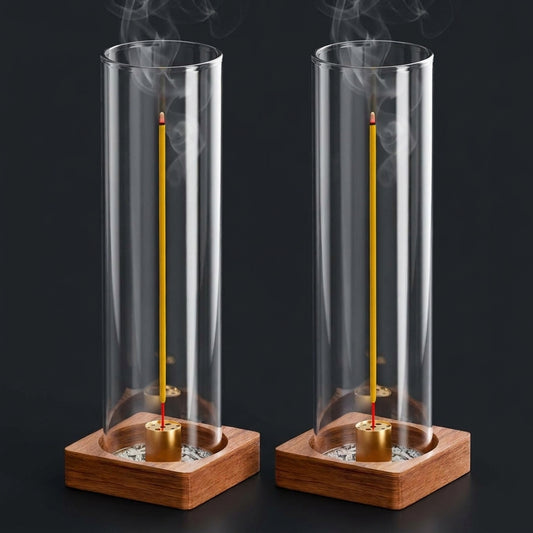 Two glass incense holders side by side, each a tall glass cylinder on a square walnut base with a brass stand inside, incense burning in both